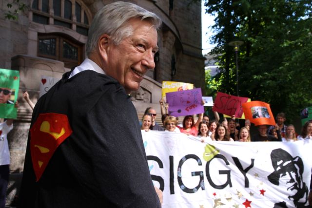 Juni 2012: Sigbjørn Johnsen mottar supermannkappe utenfor Finansdepartementet etter å ha lovet land for land-rapportering. Bilde: Kirkens Nødhjelp